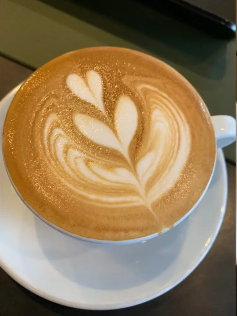 Overhead view of a latte with a rosetta pattern in a white cup and saucer